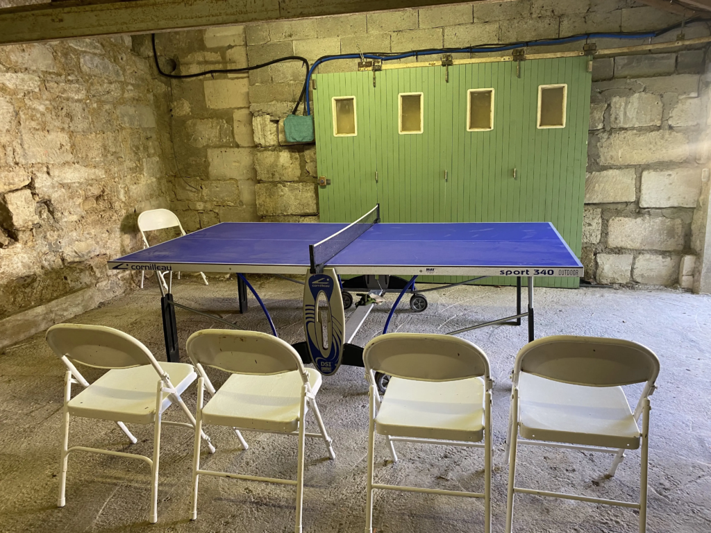 Table de ping-pong dans la cave voûtée en pierre du gîte Le Clos de l'église